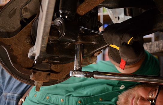 Chris using a ratchet and socket to secure the new strut to the control arm